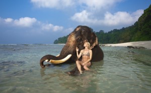 A tourist poses with an elephant at the Elephant beach.