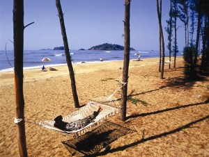 A tourist lazes around on a hammock at Devbagh beach