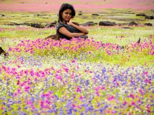 A tourist poses amidst numerous flowers in all shapes, sizes and scents.